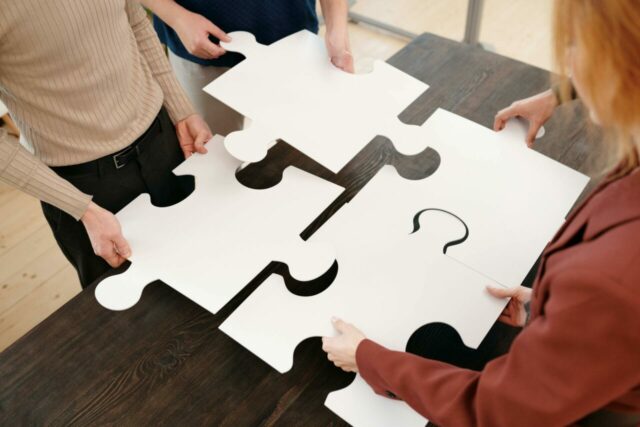 4 personnes assemblant un grand puzzle - Management de projets TPE/PME